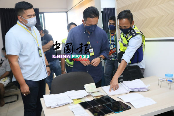 哈比比（中）在吉隆坡刑事调查组副主任纳斯里助理总监（右）及下属的陪同下，检查赌博集团的文件。