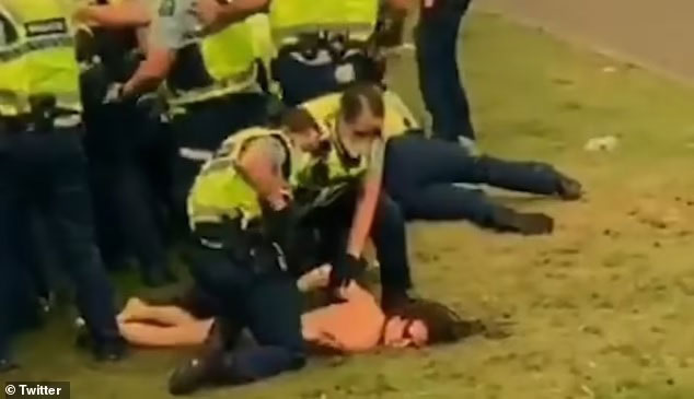 裸女示威者被警员压在草地上，并将她双手从后绑起。