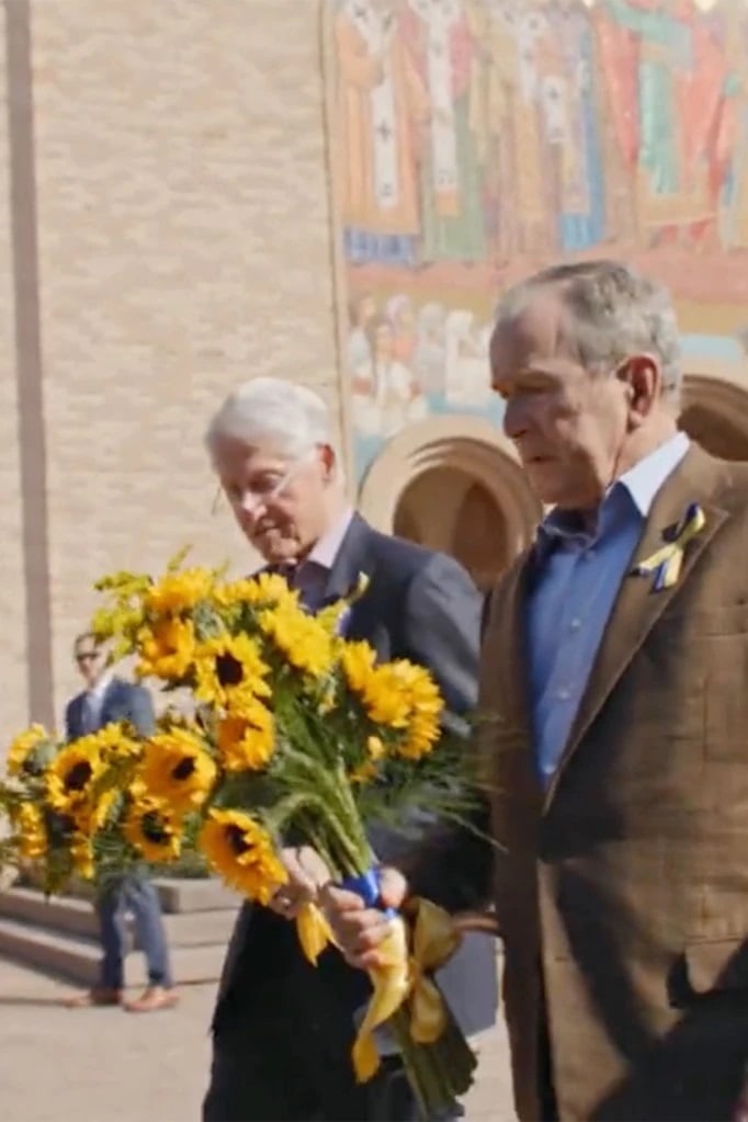 美国2位前总统克林顿（左）与小布什系黄蓝丝带、手持太阳花，一起访问乌克兰教堂。
