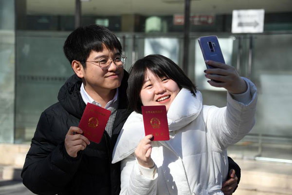 在北京市海淀区民政局婚姻登记处外，一对新人领取结婚证后拍照留念。(新华社)