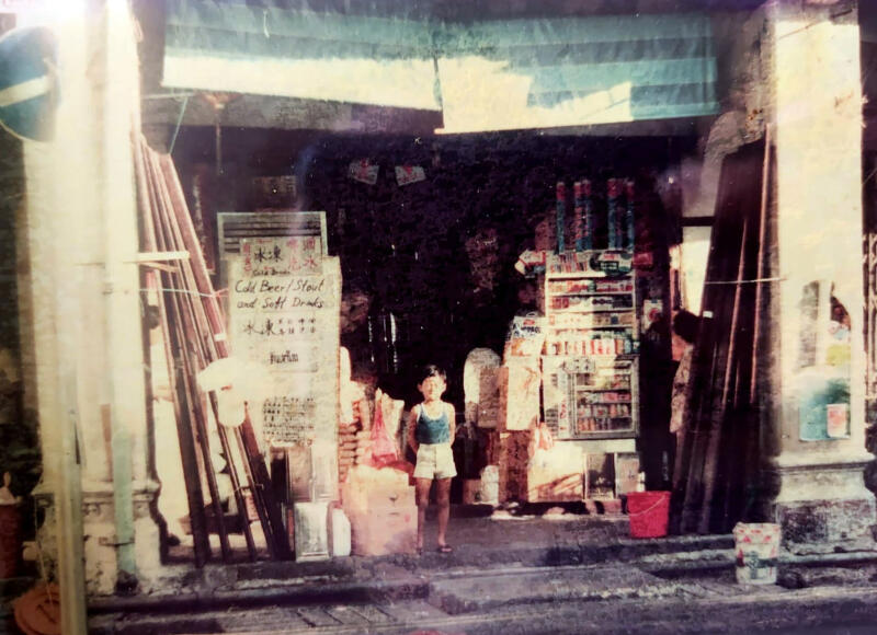 杨弓勇长子于1986年在旧杂货店前留影。（受访者提供）