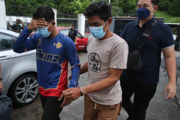 两名被告一起被戴上手铐，周日（20日）被警方押往新山法庭面控。