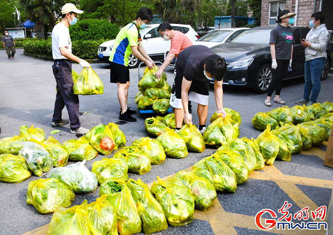 上海小区志愿者在为居民送团购物资。

