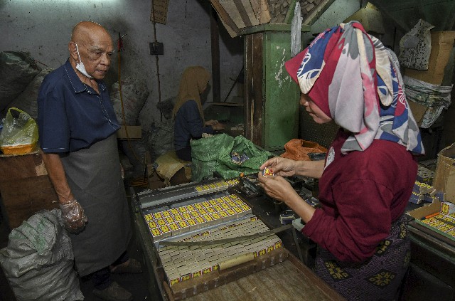 火柴厂主管马末（左）关注生产过程，女工正在往火柴盒贴上辣椒牌标签。