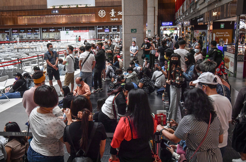 台北车站疫苗接种站周日涌现人潮，民众戴着口罩等候施打疫苗。（中央社）