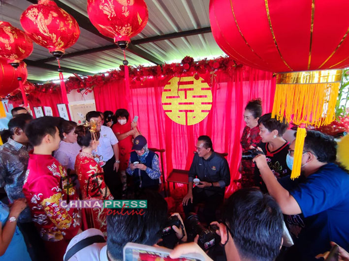 一对华裔新人，向国家团结部长拿督哈丽玛（坐者左）敬茶。