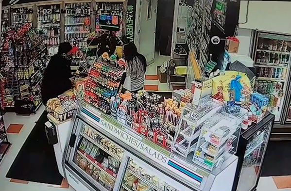 抢匪走向柜台、亮出一把手枪，命令女店员“把钱放进袋子里”。