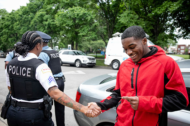 一名警察与佩里握手，感谢他冲铁轨救人的勇敢精神。（美联社）