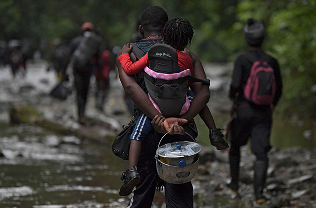 海地一名男子去年9月26日背着孩子，徒步穿越哥伦比亚达连隘口的森林，准备前往巴拿马。（法新社）