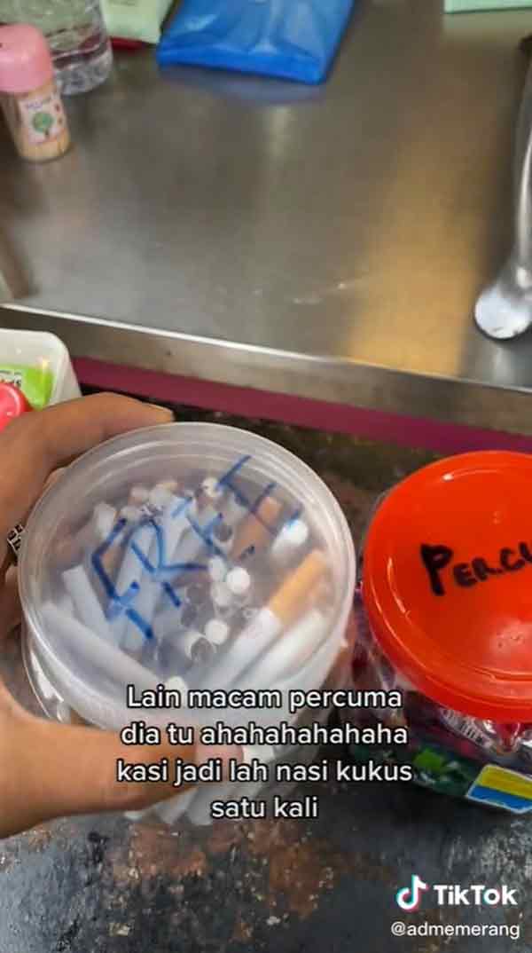 马来蒸饭档前摆放两个各装有糖果和香烟的塑料罐，盖子上注明“免费”字眼。 