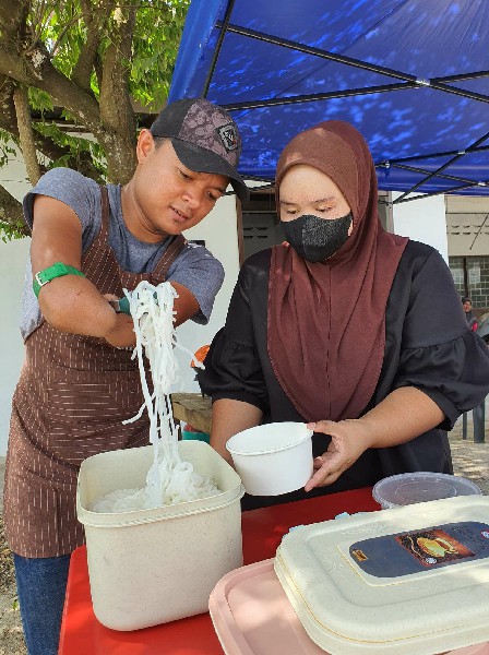 莫哈末加里（左）在食档，协助妻子售卖亚参叻沙。