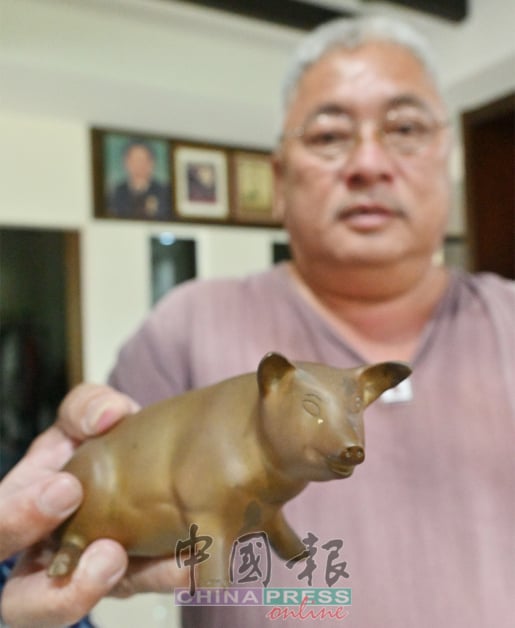 林汶辉展示所收藏的其中一只铜制猪饰品。