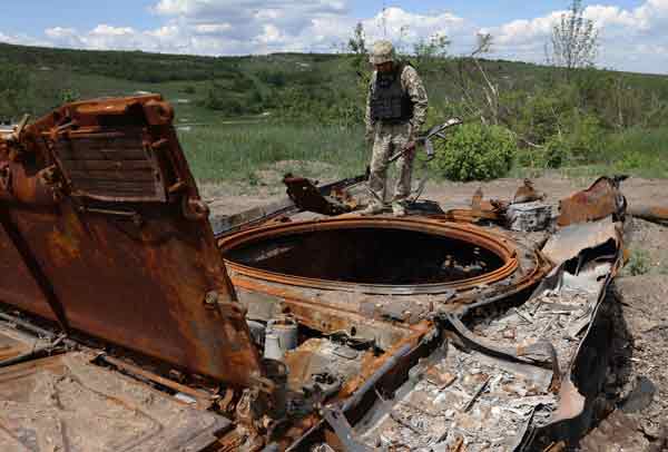 乌克兰士兵在检查一辆损毁的俄军装甲车。（法新社）
