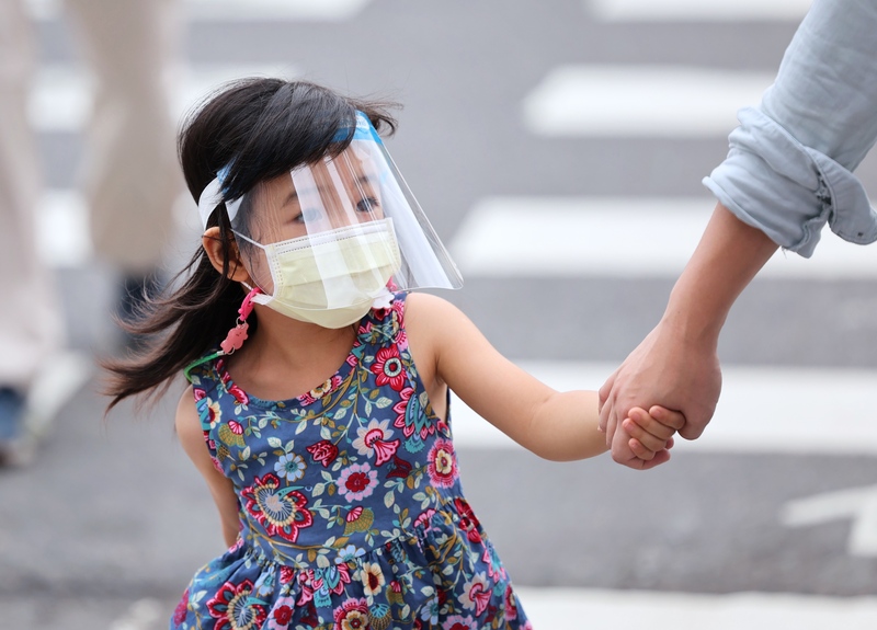 周二在台北市中正区街头，一名小朋友戴着口罩与防护面罩防疫。（中央社）