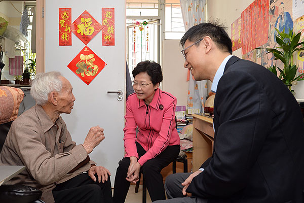 2014年，时任香港政务司司长林郑月娥（中）探访住在房委会长者单位的福伯（左），送上新年祝愿。