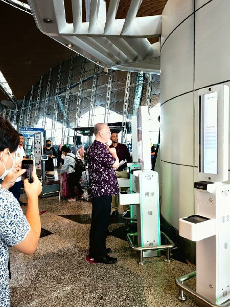 机场工作人员替魏家祥拍摄一段关于大马机场最新的生物识别登机程序的视频。
