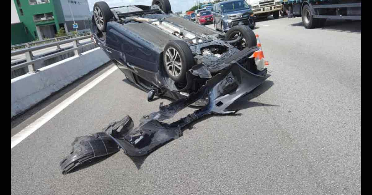 黑色的轿车翻覆后“四轮朝天”，车头严重撞毁。（《新明日报》读者提供） 