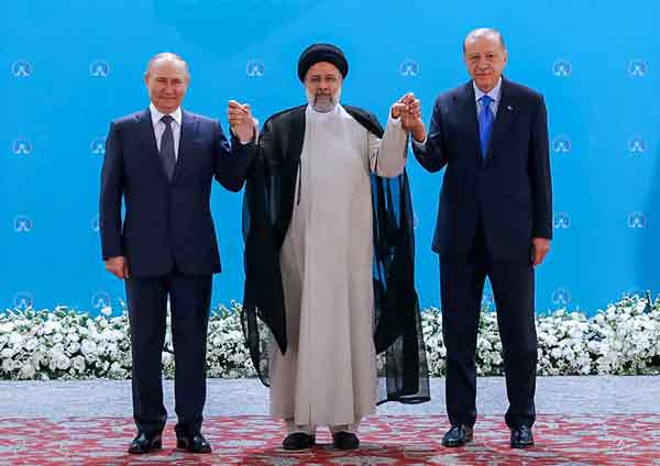 伊朗总统莱希（中），周二在峰会上，举起普汀（左）和埃尔多安（右）的手。（法新社）