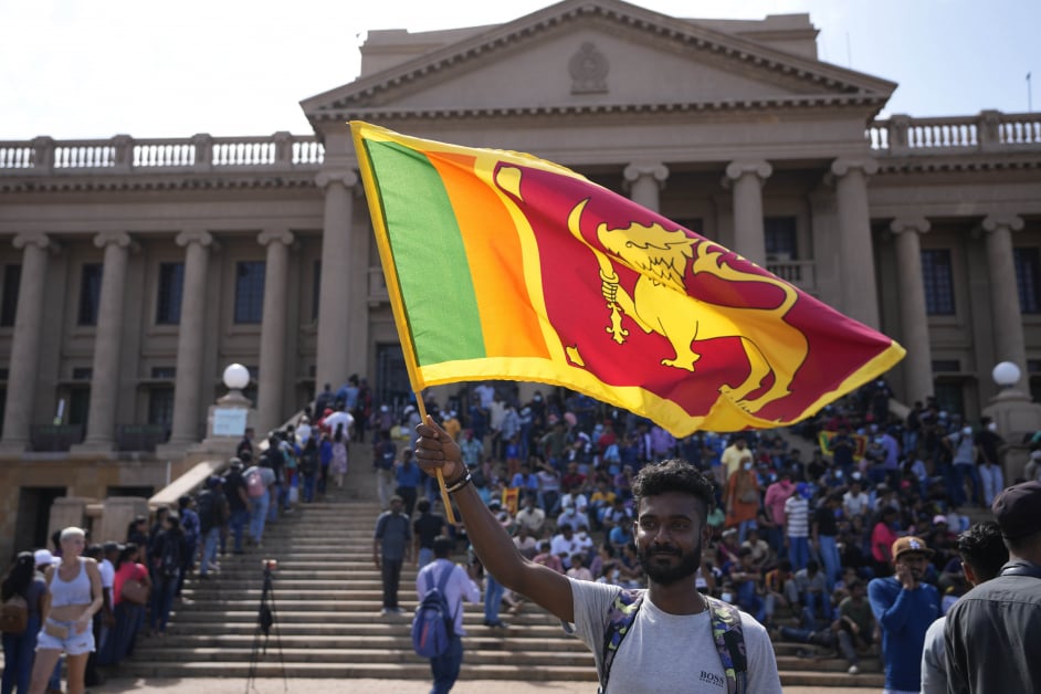 在斯里兰卡总统府外，一名男子周三挥动着斯里兰卡国旗。（美联社）