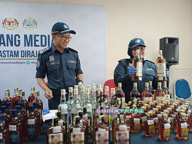 扎祖里（左）以及查案官拉依占（右）展示关税局起获的假酒。