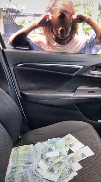 一名相信是非法移民的女孩，站在车窗外盯着副驾驶座上的一大叠50令吉钞票。 