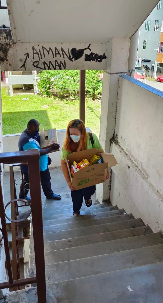 余美娜扛着一箱粮食，探望其援助的家庭。