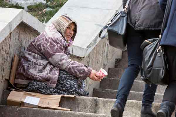 一名吉普赛妇女蹲在路边乞讨。（资料图）