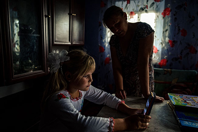 乌克兰9岁女童安东尼娜（左）在母亲娜塔莉雅的监督下上网课。（法新社）