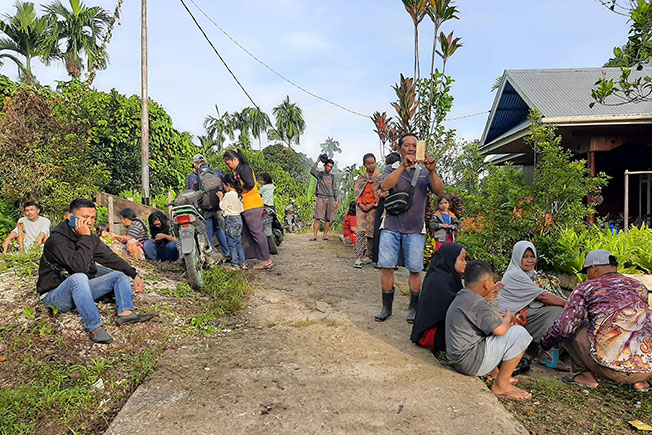 明打威群岛地震发生后，当地一个村子的村民逃出屋外，在空旷的地方避难。