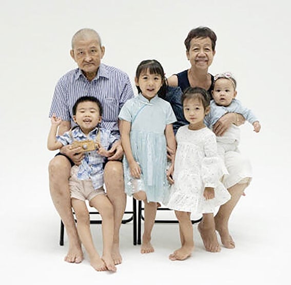 李成安（左）于7月与妻子梁少娟（右）和4名内外孙拍全家福。（受访者提供）