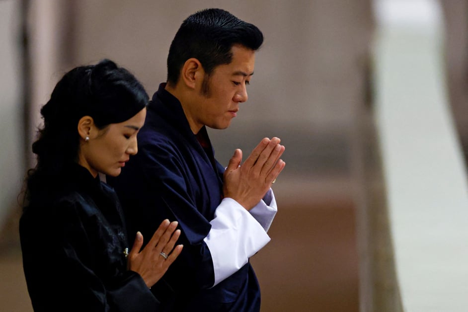 不丹国王旺楚克（右）和王后佩玛瞻仰灵柩时双手合十祈祷。（法新社）