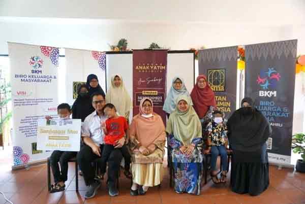 阿斯马（坐者左2）代表移交马来西亚穆斯林联盟援助冠病孤儿款项支票给受惠家庭。（图取自光芒日报）