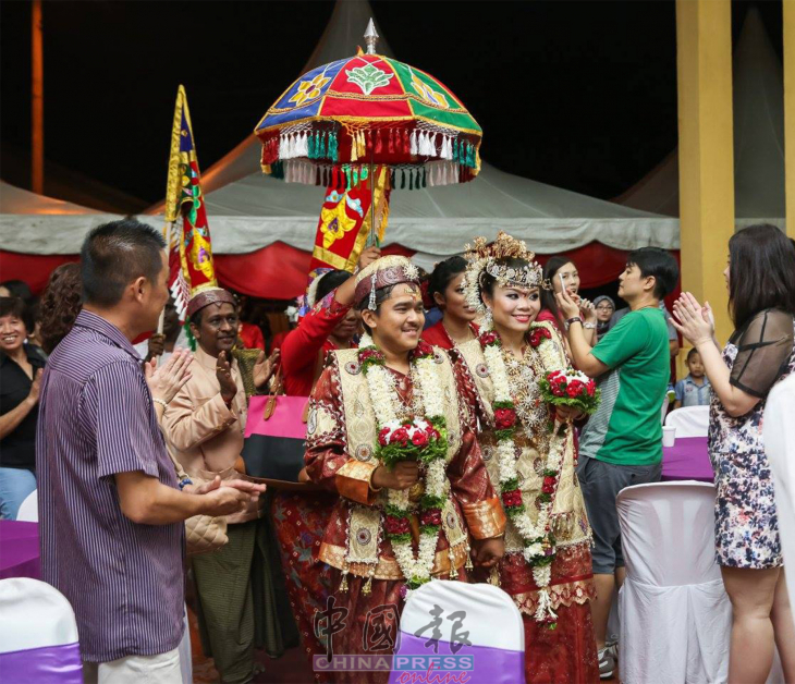一对新人在婚礼上，穿着仄迪族传统服装入场。