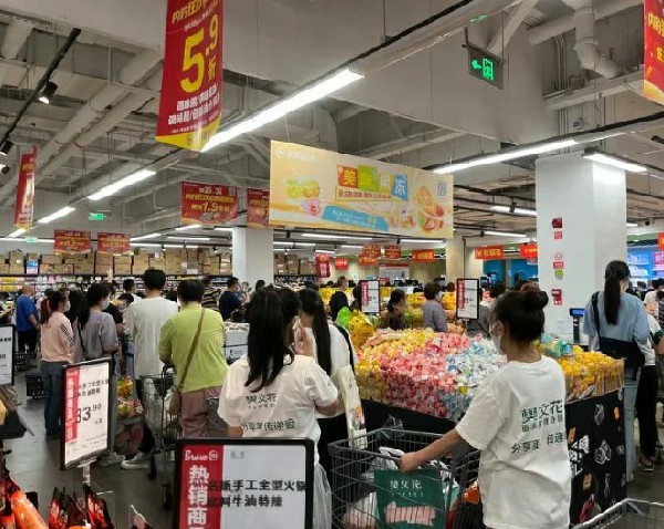 成都宣布周四傍晚6时起实行原则居家，引发市民新一轮“抢菜”。当地网民发布的照片显示，超市人流量暴增，人们排队购买生活物资。