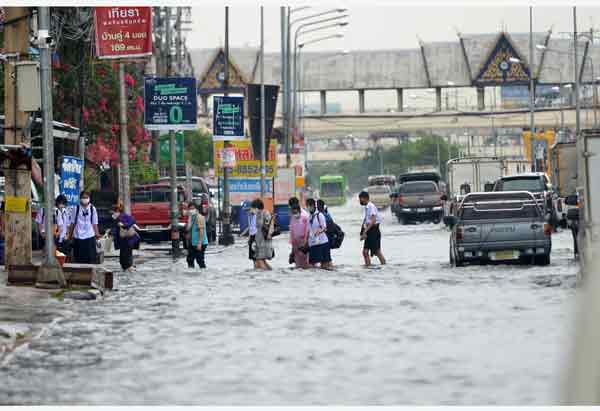 曼谷及周边地区近日降雨偏多，引发洪水。图为曼谷人们周二走过积水的街道。（新华社） 