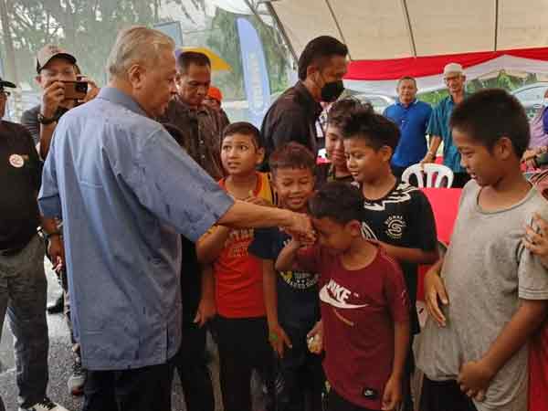 尽管被雨溅湿，依斯迈沙比里（左）仍亲切与小孩们问好。
