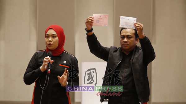 诺丽娜扎曼（左）讲解选举工作人员是如何处理所收到的邮寄选票。