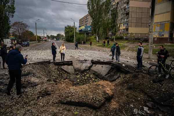 俄军周一发射导弹袭击第聂伯罗市后，当地民众围观地坑。（法新社）