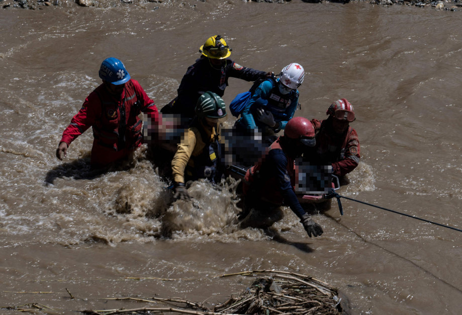 搜救人员越过湍急的河流搬运遗体。（法新社）