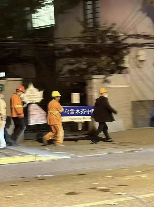 工作人员把“乌鲁木齐中路”的路牌拆走。（推特照片）