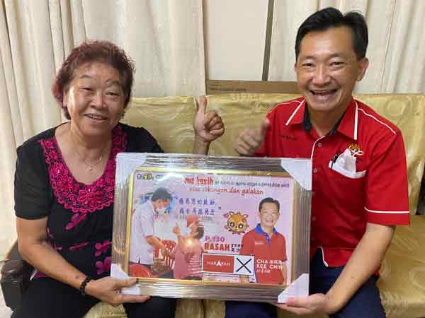 谢琪清（右）把竞选海报的设计图印成照片，送给“海报婆婆”陆慕兰纪念。