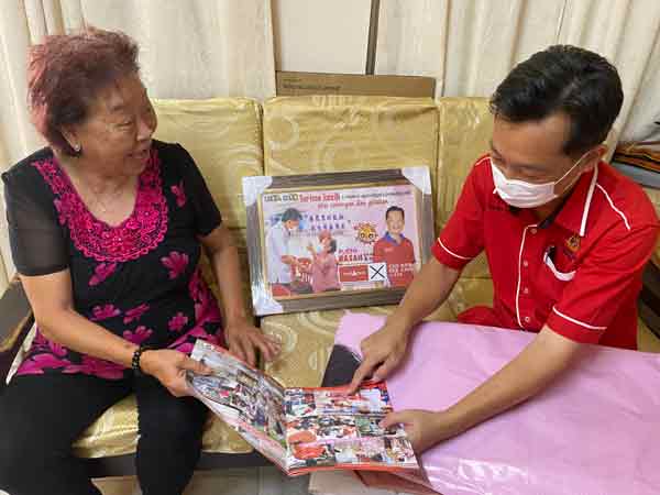 陆慕兰（左）翻阅谢琪清的竞选册子，细述当时被拍下此照片的经过。