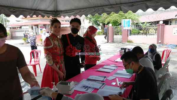 蔡芷玲（右）陪着梁志永出现在麻坡苏丹阿布巴卡女中投票站，在选民登记处登记。