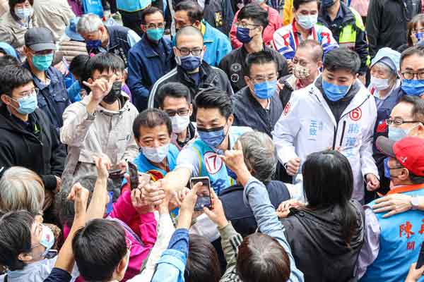 国民党台北市长参选人蒋万安（中）与支持民众握手致意，恳请赐票。（中央社）