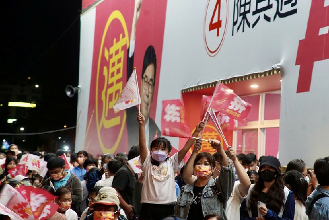 民进党高雄市长候选人陈其迈的支持者们周六在竞选总部外，有小朋友随着大人一同挥舞旗帜。（中央社）