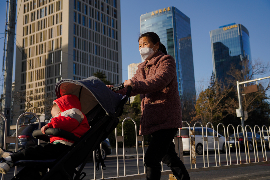 北京一名戴着口罩的妇女，周一在街道上推着婴儿车。（欧新社）