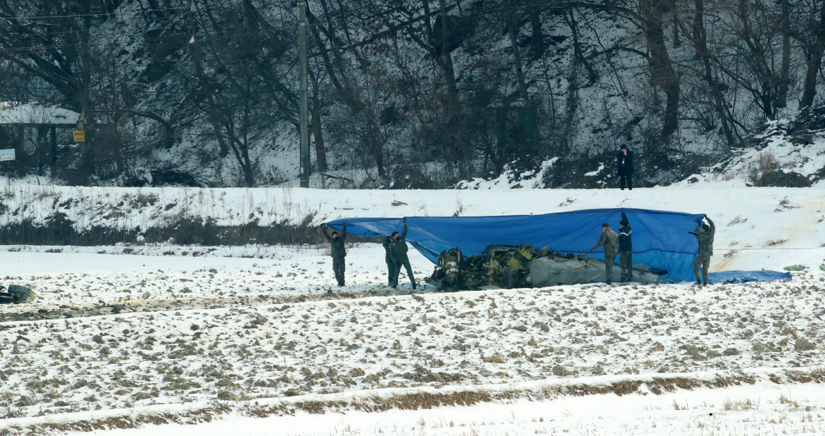 韩国军警遮盖坠毁战机。（欧新社）