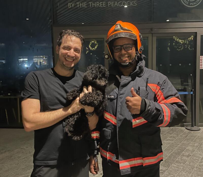 狗主抱着爱犬与其中一名消防员合影。（取自《慈母舰》） 