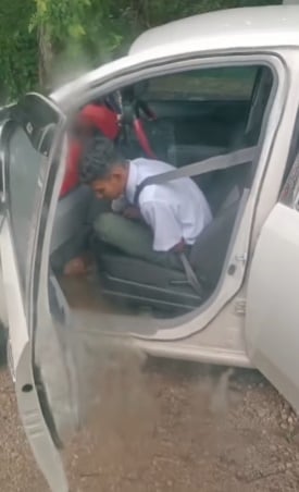 一名中学生坐在车内，无奈以鞋子将被洪水流入的轿车，扫出积水。