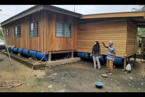 厌倦每年年尾逢雨必灾，峇卡仄阿末（右）花了7个月自建的“漂浮屋”避灾。